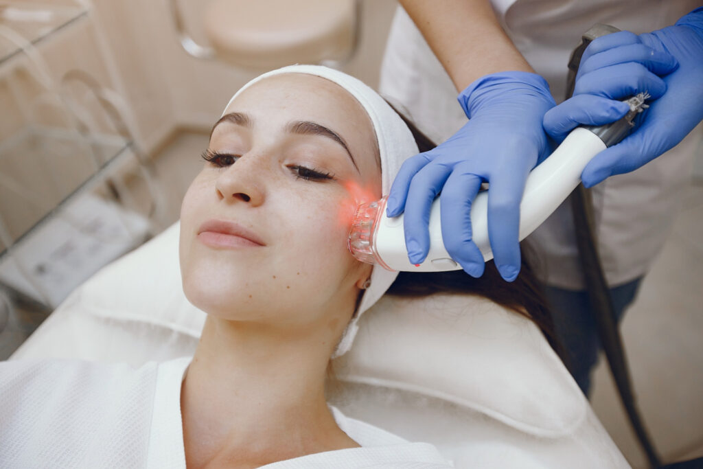 Imagem de uma mulher realizando um procedimento estético com equipamento laser